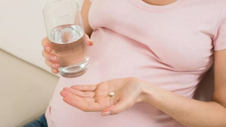 임신한 여성이 한손에 약을 들고 다른 한손에는 물컵을 들고 있는 모습