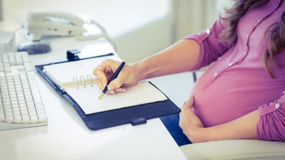 임신부가 펜을 들고 다이어리에 뭔가를 기록하고 있는 모습
