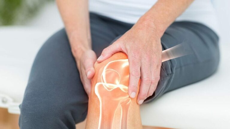 관절 통증 관련하여 어떤 사람이 앉아서 왼쪽 무릎을 양 손으로 잡고 있고 무릎이 투명하게 처리되어 뼈 부분이 비쳐지고 있는 이미지