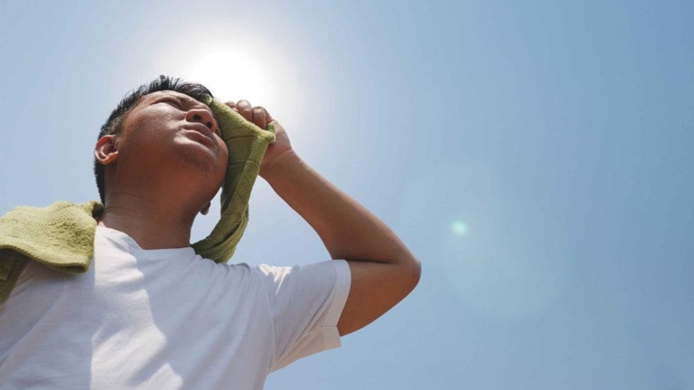 열사병 관련 한 남성이 햇빛 아래에서 수건으로 땀을 닦고 있는 모습