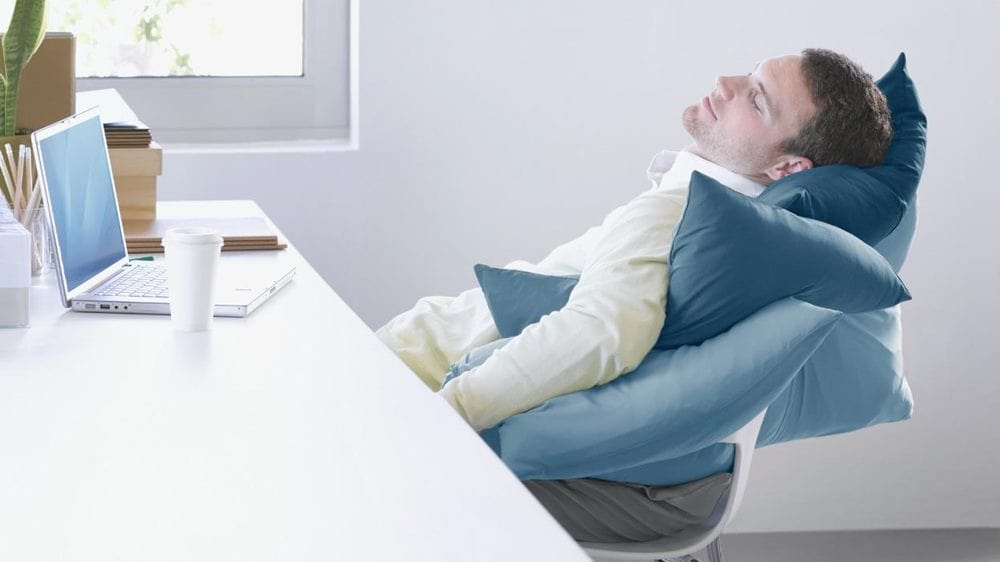 무기력증 관련 한 남자가 노트북과 커피를 책상에 둔 채 의자에 기대어 자고 있는 모습