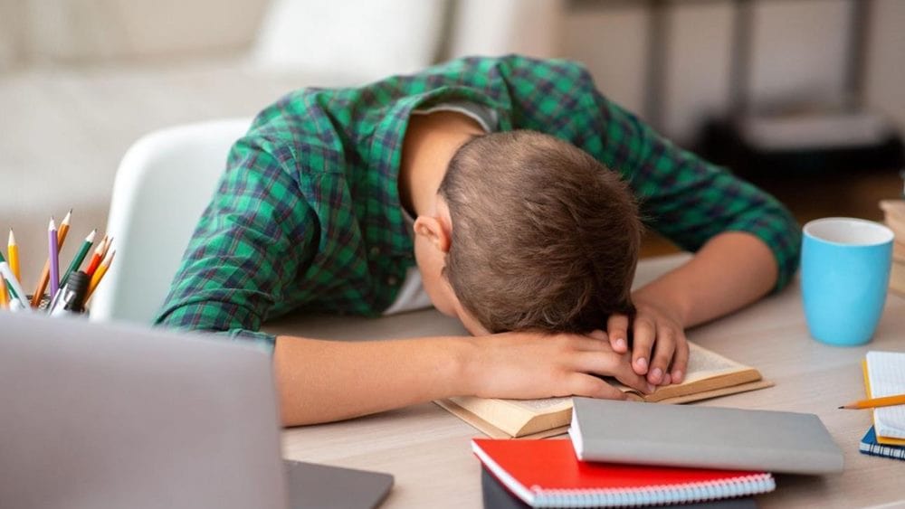 한 남성이 책상에서 책에 머리를 파묻고 자고 있는 모습