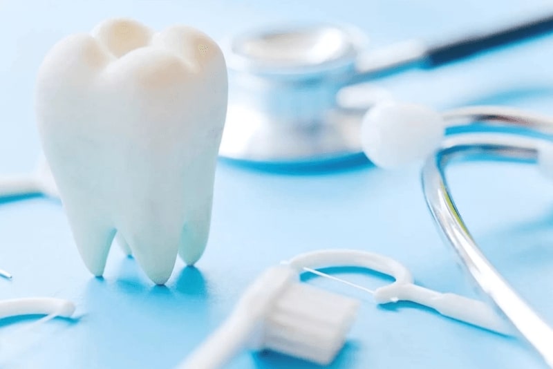 앞니 임플란트 치료 관련 치아 모형과 칫솔, 청진기 등이 놓여진 이미지