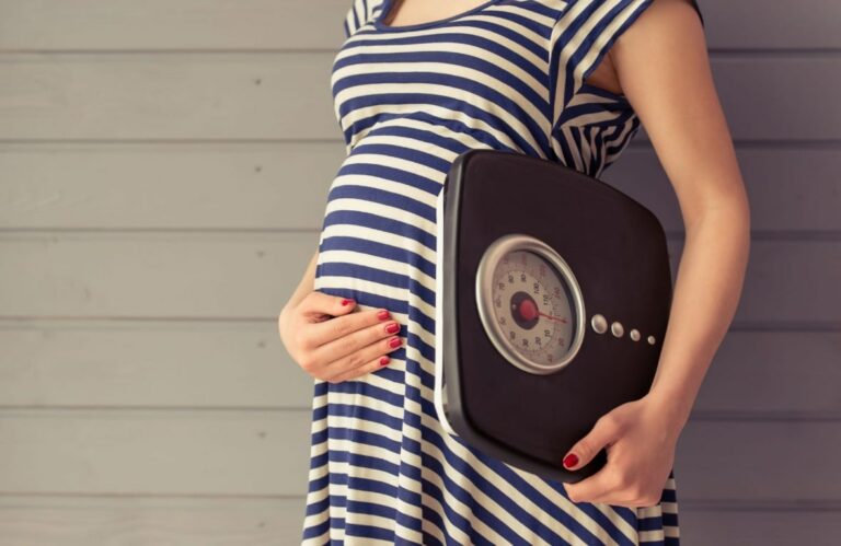 임산부 체중증가 관련 줄무늬 옷을 입은 임산부가 한 손을 배에 올리고 다른 한 손으로는 체중계를 들고 있는 모습