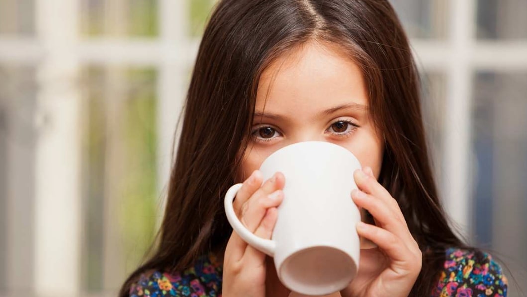 어린이가 컵을 들고 커피를 마시고 있는 모습