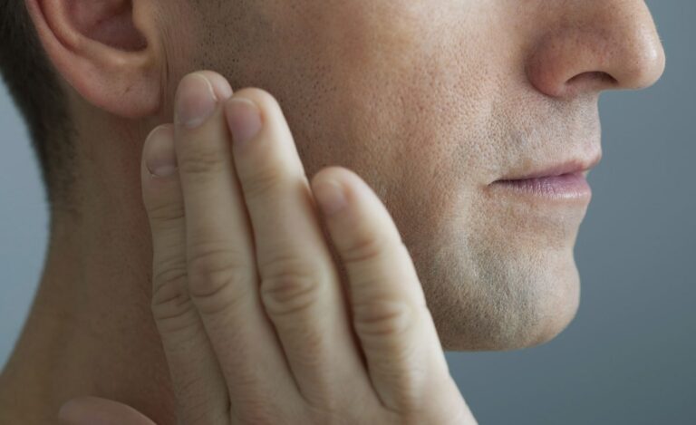 오른쪽 귀밑 턱 통증 관련 남성이 오른쪽 귀밑 턱 부분을 손으로 만지고 있는 모습