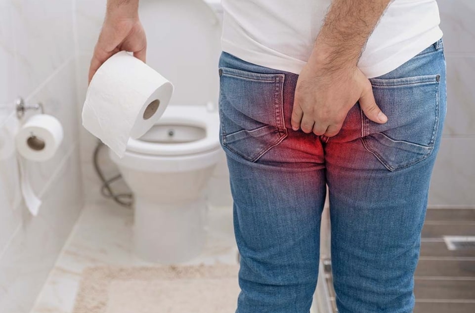 남자가 화장실에서 휴지를 들고 엉덩이쪽을 잡고 있는 모습